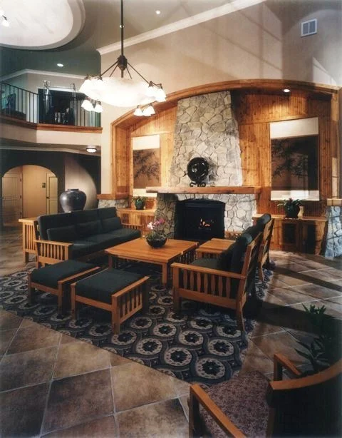 Lodge lobby with stone fireplace, craftsman furniture, and vaulted mezzanine