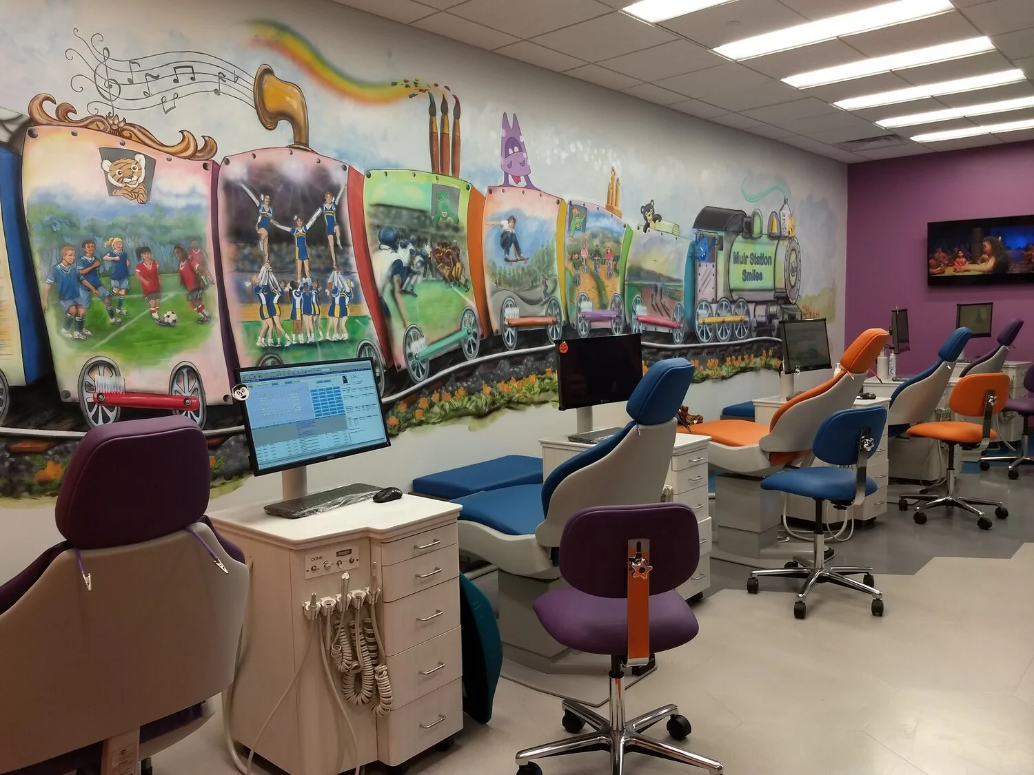 Pediatric dental bay with custom train mural and colorful seating