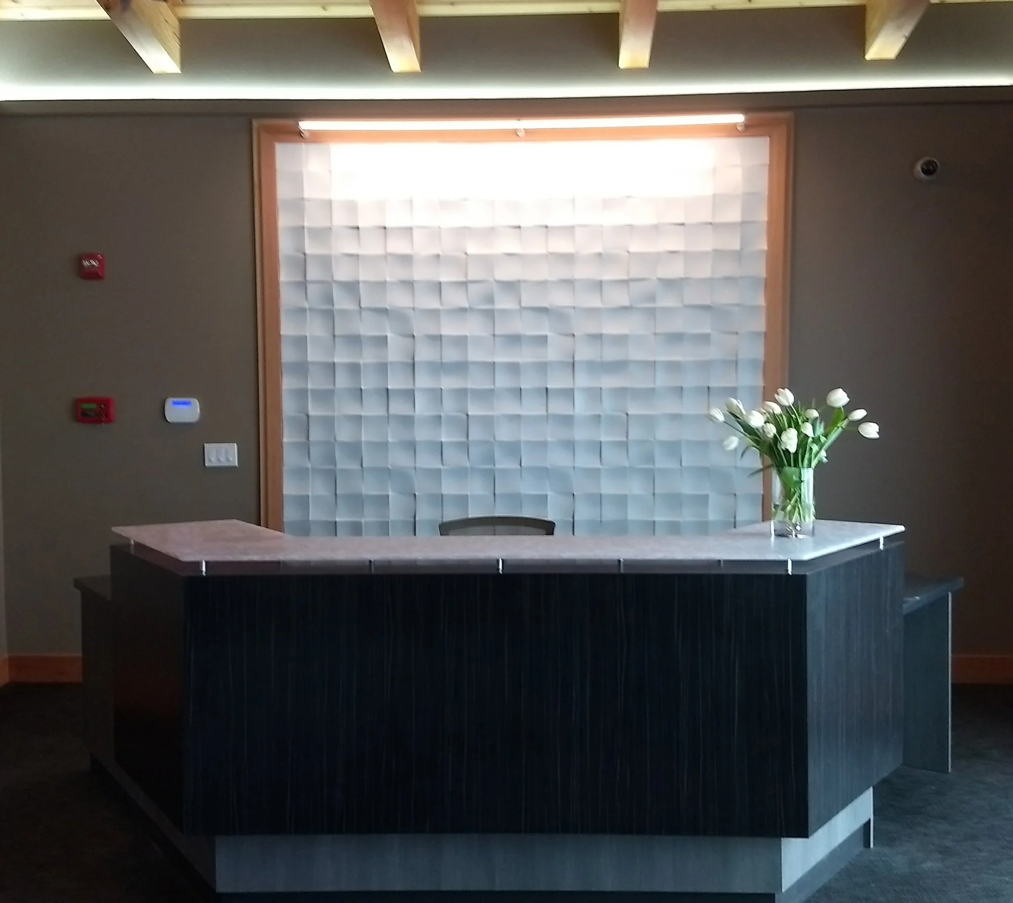 Office reception with dimensional textured wall feature and exposed beam ceiling