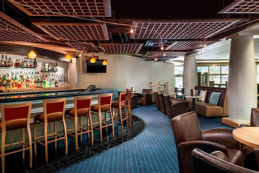Upscale restaurant bar with curved counter, leather seating, and pendant lighting